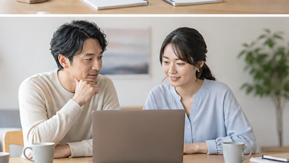 家計や仕事についてノートパソコンを見ながら話す二人